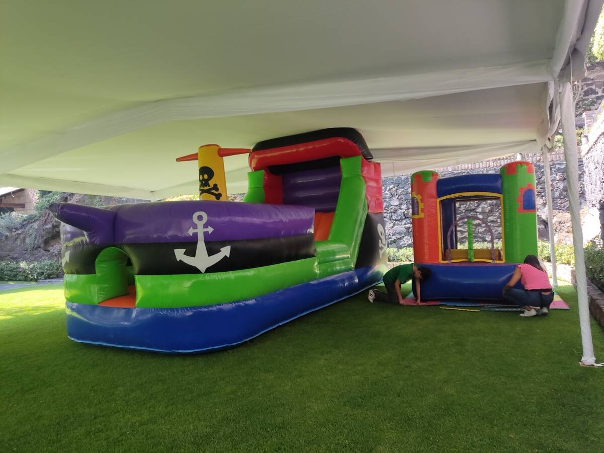 Niños jugando a los piratas alrededor del barco pirata inflable en una fiesta en CDMX